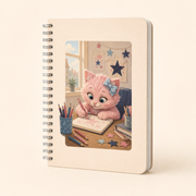 Cream spiral notebook with Pink Kitten sketching at a tidy desk among pencils and paper stars